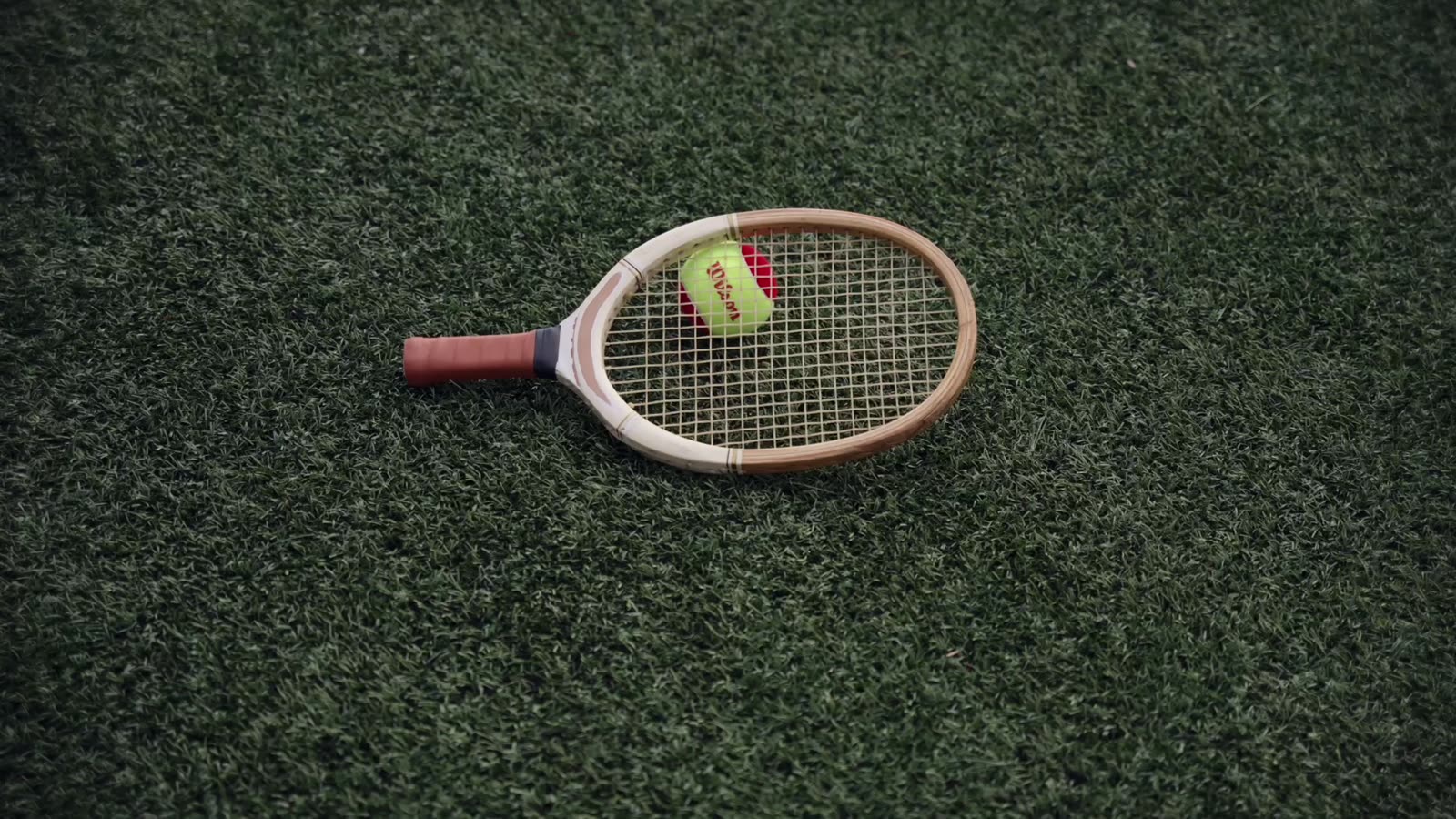 A racket and ball resting on turf